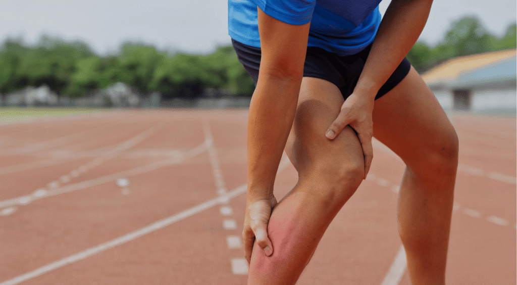 An athlete standing on an Indore sports field holding his injured knee, indicating a potential need for ACL rehabilitation in Indore to recover safely.