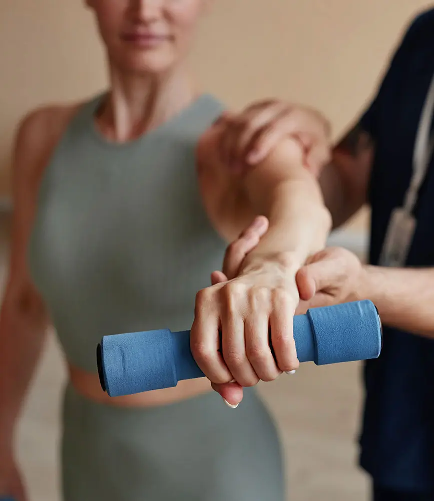 A therapist at Dr Manisha Physiotherapy Clinic assisting a patient with weighted shoulder flexion as part of a pre surgery physiotherapy in Indore program to build muscle reserve before an operation.